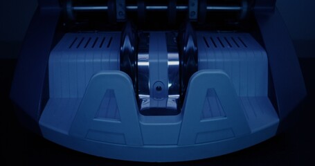 The calculating machine counts a stack of dollar bills on a dark background, front view, close-up