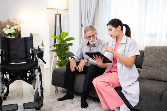 Young professional confident skilled woman doctor visiting Caucasian senior patient man at home for treatment control care giving. Nurse talking to senior patient and using tablet. Healthcare concept
