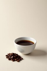 Obraz premium Aromatic Dark Roast Coffee in a Small White Cup Beside a Pile of Roasted Beans