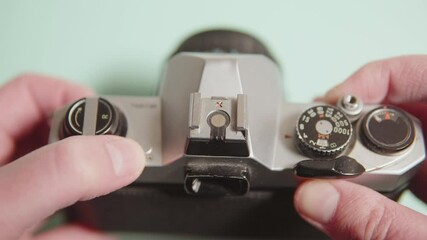 Vintage analog camera with hands carefully adjusting intricate settings