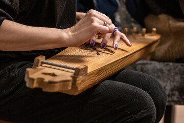 Fingers of a girl playing kankles, Lithuanian plucked string instrument belonging to the Baltic box zither family known as the Baltic psaltery, in Latvian kokles, Estonian kannel, Finnish kantele