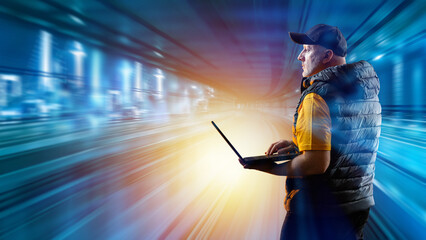 Man with laptop on city street. Speed effect near engineer. Guy in cap in city at night. Urban transport system designer. Man with computer in dark vest. Transport infrastructure designer