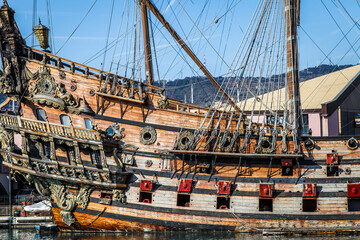 A large ship is docked in a harbor in an aquarium in Genoa, Italy. There are several smaller boats...