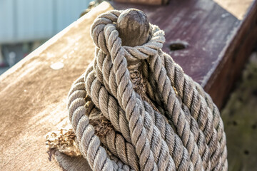 Fototapeta premium A rope is tied to a wooden post. The rope is frayed and has a knot in the middle