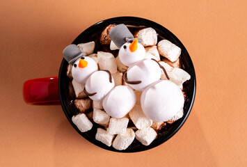 Top view mug with a hot drink and marshmallows in form of snowman on a white table
