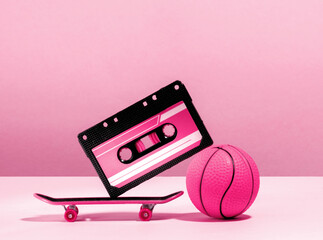 Creative still life with audio tape, skateboard and basketball ball in pink colors