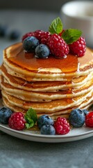 Delicious stack of fluffy pancakes topped with berries and syrup