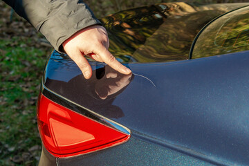 Man looking examining scratch on his car trunk.Unexpectable vehicle damage trouble accident.Road...