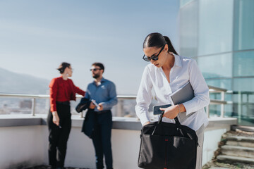 A group of business people engaged in a conversation on a high-rise tower balcony. The setting is...