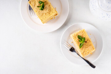 Homemade Napoleon cake slices, layered mille-feuille cake with vanilla creamy custard, tasty delicious puff pastry, on serving plates with forks, copy space