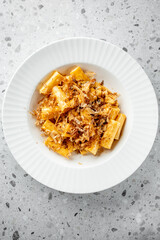 A creamy plate of rigatoni pasta topped with a generous sprinkle of bonito flakes, presenting a delicious fusion of flavors and textures, perfect for food lovers and culinary enthusiasts.