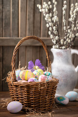 Decorated Easter eggs in a basket and vase with pussy willow branches