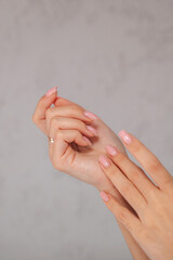 A close-up of delicate female hands with a light manicure, highlighting skincare, hydration, and beauty treatment with hand cream