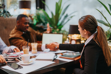 A professional group engaging in discussion and collaboration at a cozy cafe, exchanging ideas and sealing an agreement.