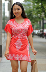 Sexy young Asian woman walking with her shopping bag through the city