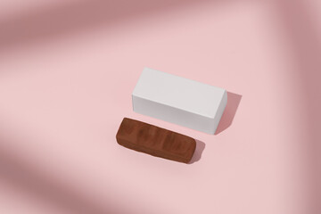 White mockup box and chocolate protein bar on pink isolated background. Concept of advertising and packaging of confectionery and sweet products, packaging design