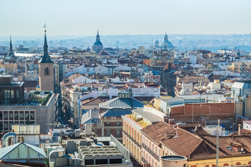Fototapeta premium Panoramic view of Madrid historic center with a focus on traditional rooftops, churches, and iconic domes. This aerial image captures the essence of the city's architectural beauty from above