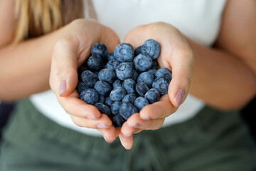 Blueberries. Close-up female hands with a handful of ripe blueberries.