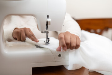 Close-up of a woman’s hand sewing with a sewing machine, ideal for DIY, crafting, home decor, and sewing enthusiasts.