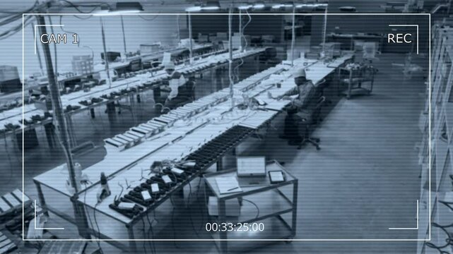 Wide high-angle CCTV surveillance camera shot of two diverse lighting factory specialists working in workshop, assembling industrial lamps, checking technical drawings and specifications on laptop