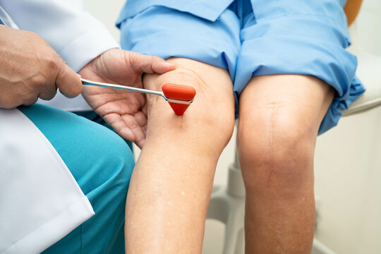 Asian doctor knock on knee reflex nerve for check and treatment senior patient in hospital.