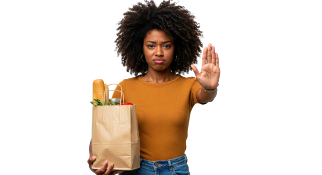 A young woman with curly hair stands holding a brown grocery bag filled with vegetables. She gives a stop gesture with her hand, expressing disapproval or refusal