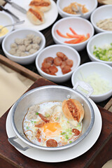Breakfast with fried eggs in a pan with bacon and vegetables on dark background, top view 
