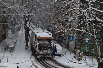 Moment of a storm with strong wind and heavy snowfall on a narrow street with parked cars and a garbage truck, Sofia, Bulgaria 