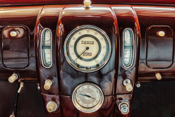 Close up of a fourties interior of a maroon American classic car with speedometer and clock