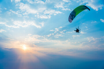Paraglider soaring through the sky during sunset against a backdrop of clouds