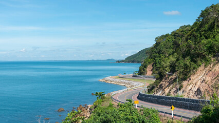 Coastal winding road offers stunning views of the ocean and hillside on a clear sunny day