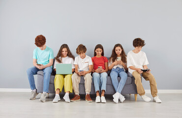 School pupil children group stuck to mobile phone gadgets, laptop device, young student friends and classmates girls and boys computer addiction, excessive usage, obsessive and compulsive use