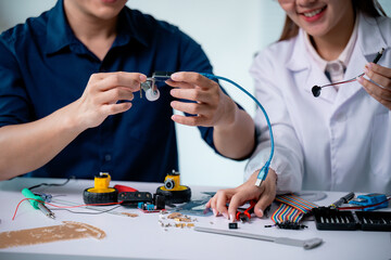 Two engineers collaborating in a laboratory, assembling electronic components for a robot. Utilizing various tools and parts, they focus on developing an innovative project