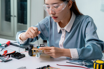 Female engineer adjusting robotic toy car with screwdriver, wearing safety glasses in high-tech lab surrounded by mechanical components