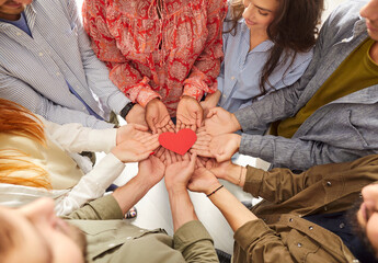Close up of a group of volunteers hands from diverse backgrounds holding a red heart together in a circle. Symbolizes love, community, and support, particularly around Valentine Day.