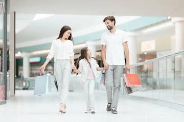 Family, father, mother and daughter are walking to another store in shopping mall.