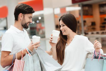 Man and woman in shopping mall. Couple is drinking coffee.