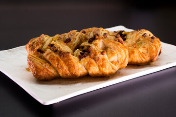 Fresh delicious puff pastry with maple syrup and nuts on black background