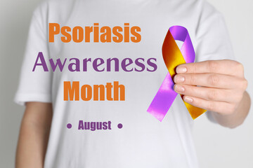 Psoriasis Awareness Month (August). Woman holding orange-orchid awareness ribbon on white background, closeup