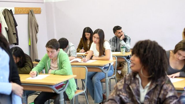 Teacher supervising students taking exam in classroom