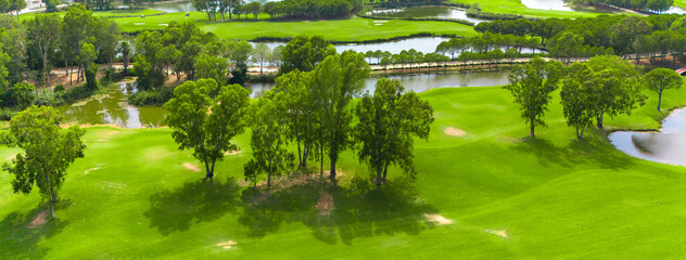 Panoramic view of a golf course with water features, sand traps, and scattered trees