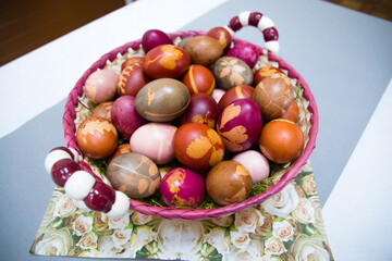 A bag filled with colorful Easter eggs naturally dyed with botanical leaf patterns, placed in a decorative vase. A unique and rustic holiday composition.
