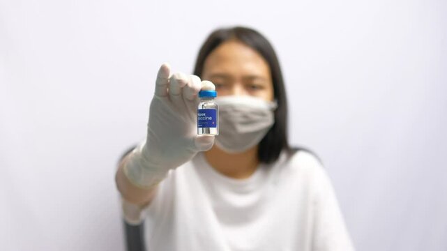 A woman is holding a vial MPOX vaccine injection inside a room. Health and medical concept