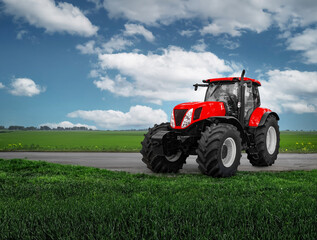 A red tractor is driving down a road in a field
