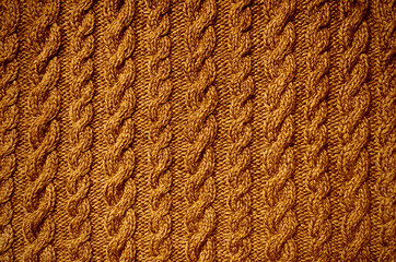 Textile background orange crochet close-up. Knitted needlework with aran pattern