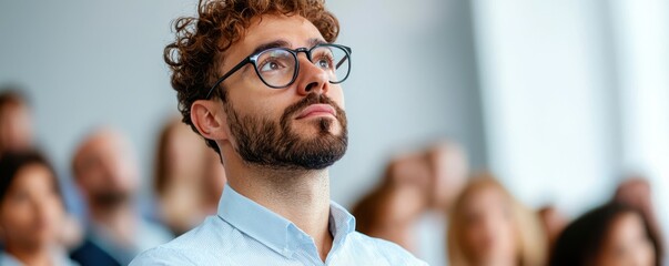 Leadership development training confidence concept. A thoughtful man listens intently during a presentation, surrounded by a diverse audience in a bright, modern setting.