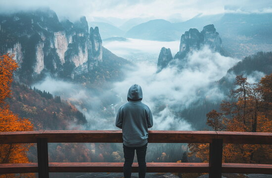 A man gazing into the distant misty mountains in an alpine landscape, with a look of contemplation amidst the fog, capturing the peaceful yet powerful atmosphere of nature.


