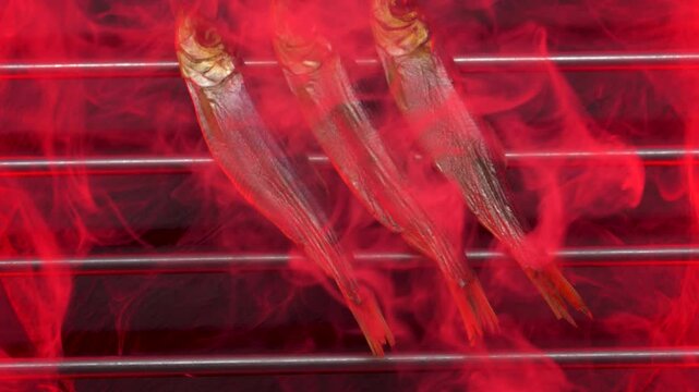 Hot smoked whole herrings on kitchen table. smoked fish isolated on a black background. Smoke