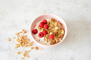 Granola with Yogurt and Raspberries in pink bowl top view
