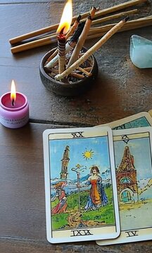 A deck of tarot cards is on a table with a candle and some herbs. The cards are arranged in a row and the candle is lit. Scene is mysterious and spiritual